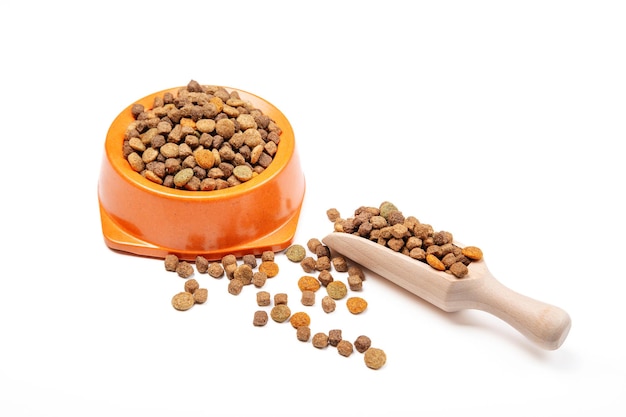 Dry food for cats and dogs in a bowl with a scoop for food on a white background.