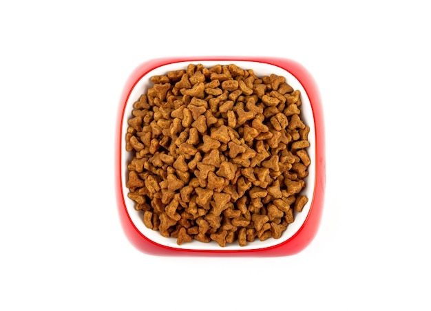 Dry food for cats and dogs in a red bowl on a white background top view