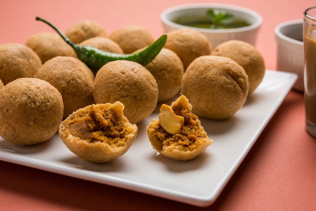 Foto il kachori alla frutta secca è una palla piccola e rotonda ripiena di masala e anacardi, ecc., servita con ketchup e tè caldo, prodotto haldiram