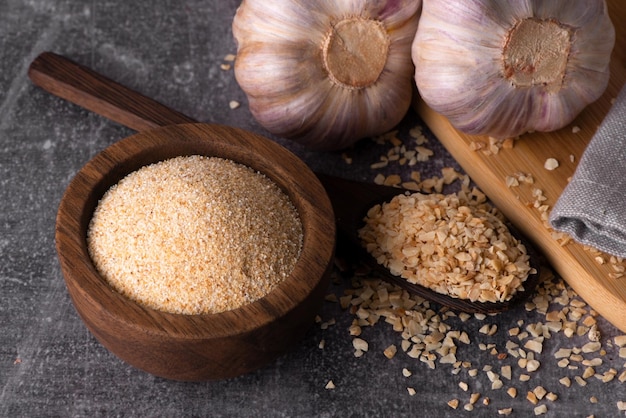 Granuli di aglio secco aglio speziato aglio secco in polvere in una ciotola di legno e cucchiaio