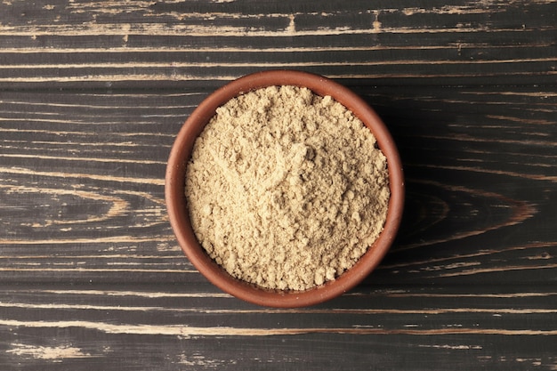 Dry ginger in a bowl on a wooden background.