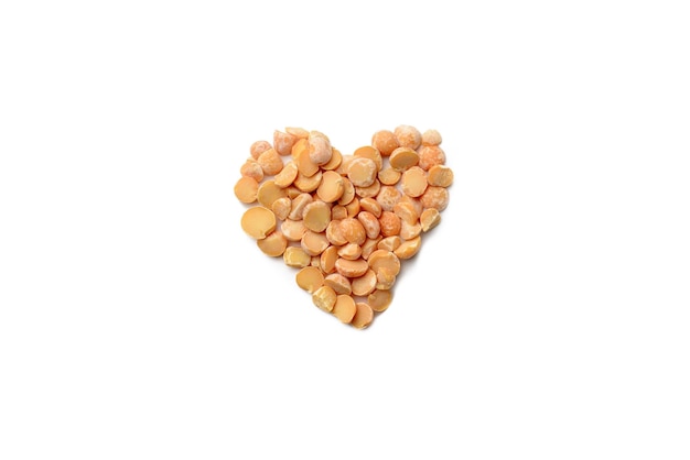 Dry grains of peas stacked in the form of a heart on a white isolated background top view