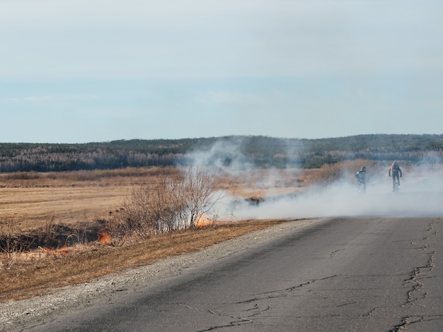 Dry grass burns on the field in hot weather. Dangerous forest fires, disaster. Moat with water, fire prevention, fire safety equipment.