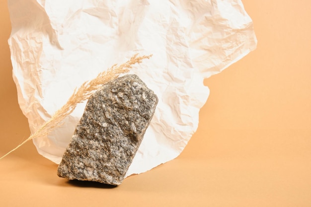 Dry grass, crumpled white paper and natural stone on a beige background, background for the presentation of your organic product mock up copy space