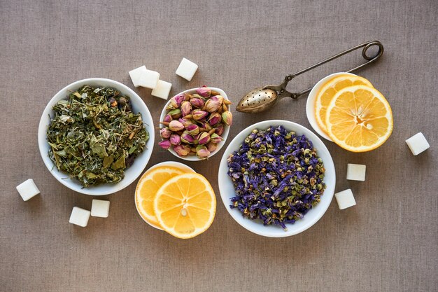 Dry herbal and flower tea in bowls on a brown background