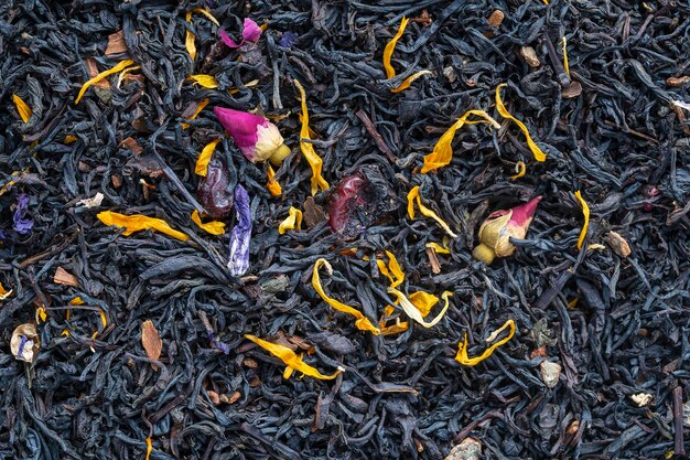 Dry herbs tea with fruit and flower petals as background top view