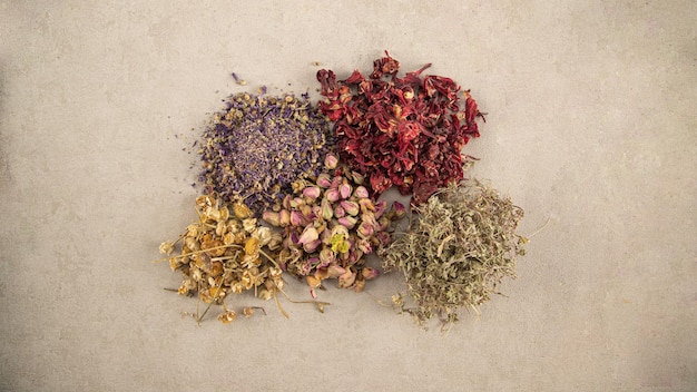 Dry herbs tea with fruit and flower petals as background top view