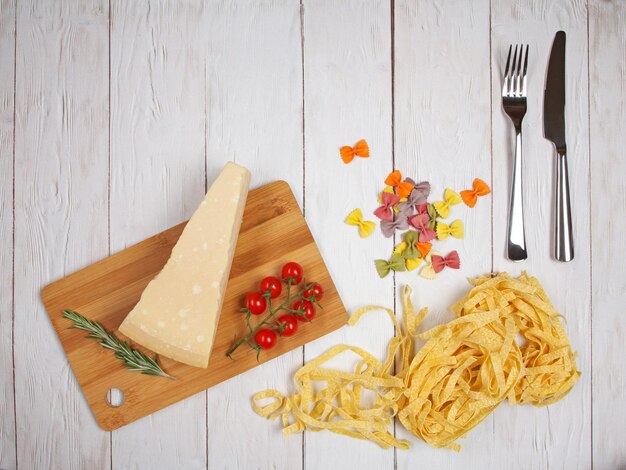Foto fettuccine di pasta italiana secca e farfalle con pomodori e formaggio al rosmarino