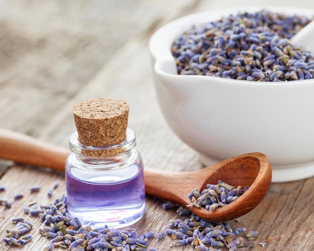 Dry lavender flowers in mortar and bottle of essential oil Selective focus