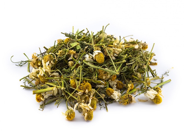 Dry leaves and chamomile flowers on white surface