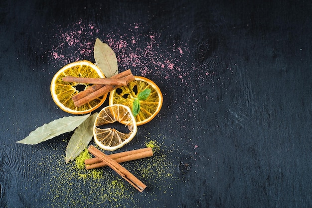 Dry lemons and spices on black wooden background