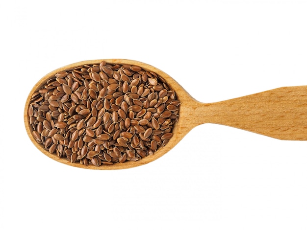 Dry Linum seeds in a wooden spoon on a white background.