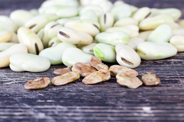 Dry lungs and wrinkled bean seeds, lie along with fresh grains on a black table, closeup