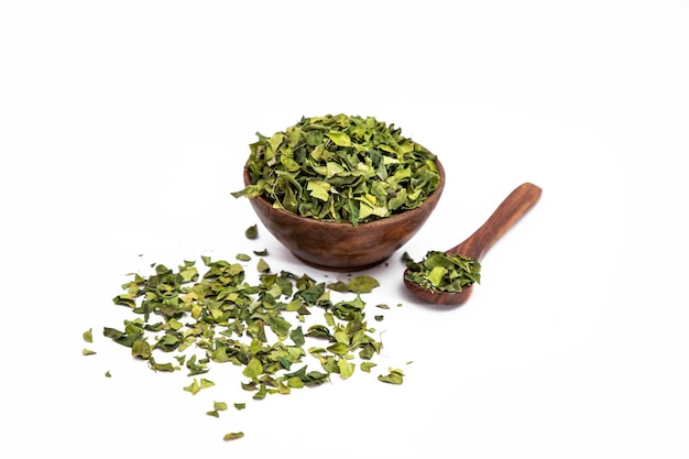 Dry neem leaves or Azadirachta indica in wooden bowl on white background with wooden spoon