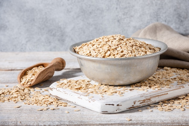 Dry oat flakes in vintage bowl on wooden table