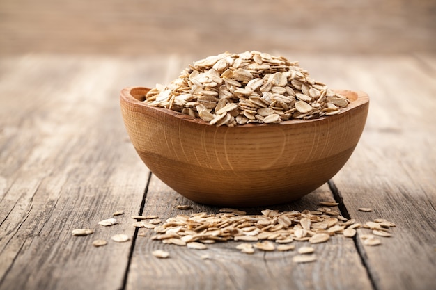 Dry oat flakes in wooden bowl