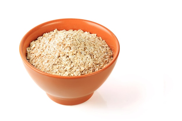 Dry oat grains in brown clay bowl