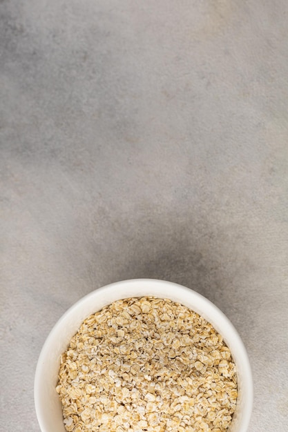 Photo dry oatmeal in a white bowl on a light background