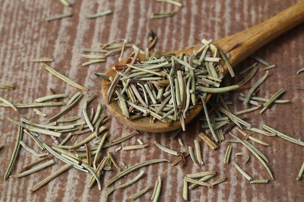 Dry organic background or texture of rosemary leaves Healthy food concept a wooden spoon with rosemary