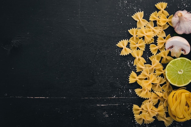 Photo dry pasta farfalle with vegetables on a wooden background top view copy space