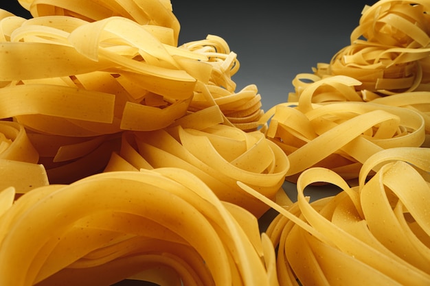 Dry pasta noodles on dark background macro photo