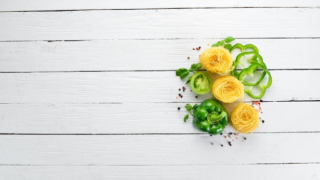 Dry pasta Pasta and fresh vegetables Top view On a white wooden background Free copy space