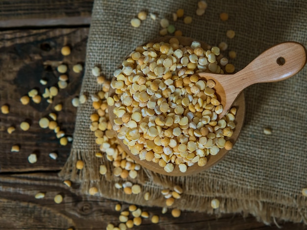 Dry peas in a wooden bowl on an old wooden table close-up with copy space