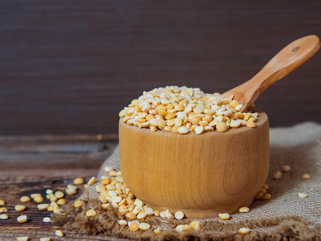 Dry peas in a wooden bowl on an old wooden table close-up with copy space