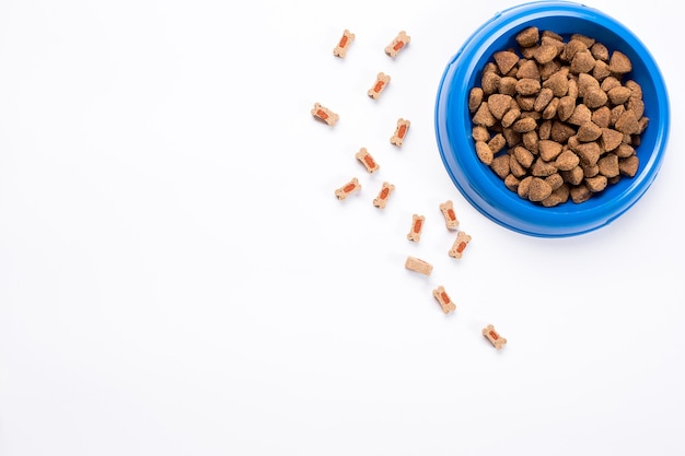 Dry pet food in bowl on white background top view