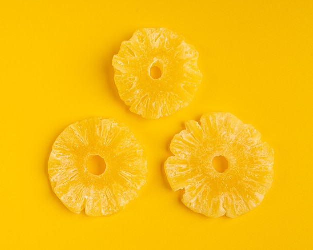 Сухие кольца ананаса изолированные конфеты ананасы обезвоженные желтые сахарные фрукты цукаты круги сухой ананас на желтом фоне