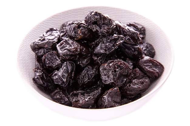 Dry prunes in a white dish on a white background  isolated items and products