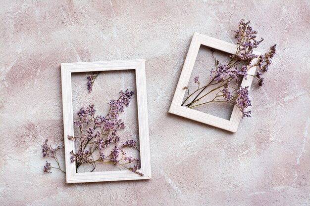 Fiori viola secchi in due cornici di legno bianche su uno sfondo strutturato. cartolina d'epoca di auguri romantico. vista dall'alto