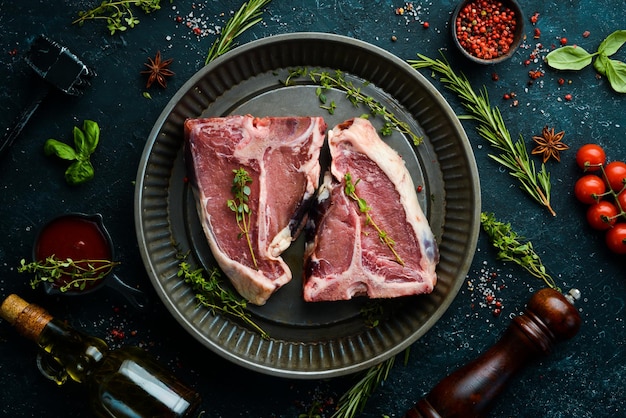 Dry raw Tbone steak in a metal baking dish on a black stone background Top view Rustic style