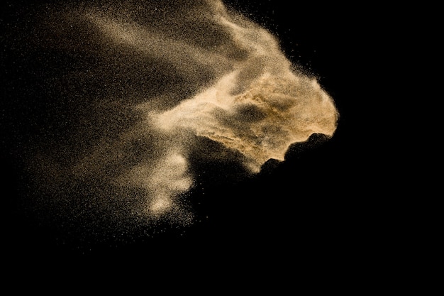 Dry river sand explosion. Golden color sand splash against  black background.