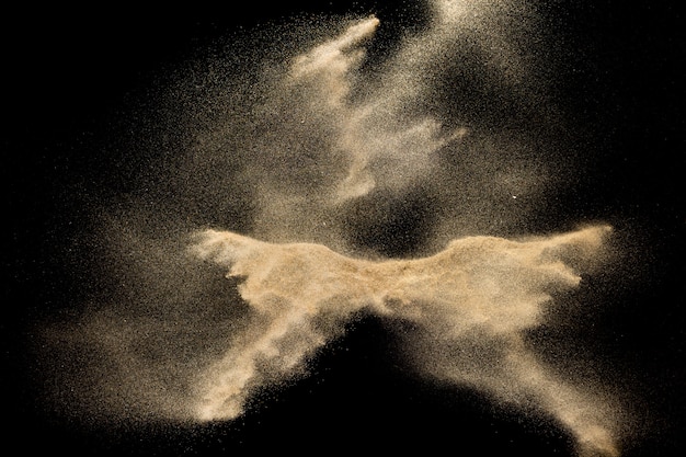 Dry river sand explosion. Golden colored sand splash against black background.