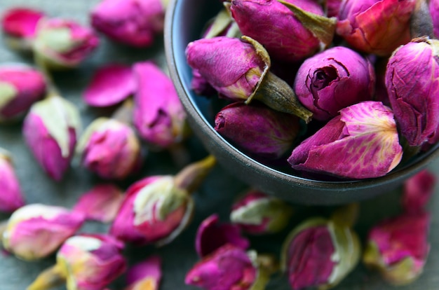 Dry rose buds flowers in a bowl on old wooden table