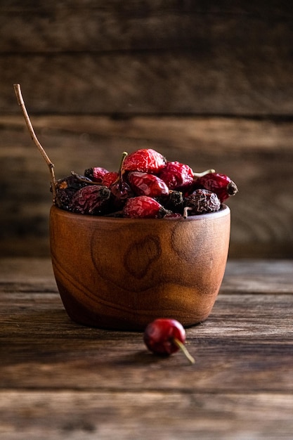 Dry rose hips in a wooden cup overturned on the kitchen table.