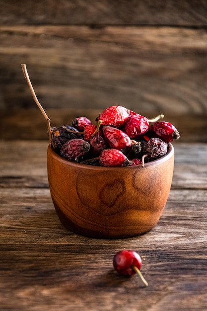 Dry rose hips in a wooden cup overturned on the kitchen table.