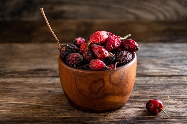 Dry rose hips in a wooden cup overturned on the kitchen table.