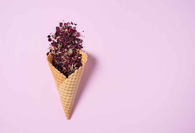 Dry rose tea falls out of a waffle cone