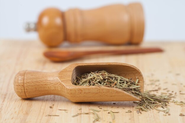 dry rosemary herb in wood scoop on wood background.