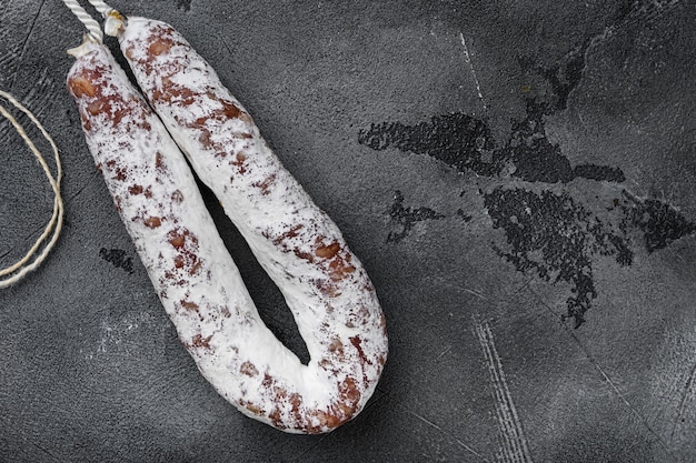 Dry salami sausage fuet on grey textured background, flat lay with copy space.