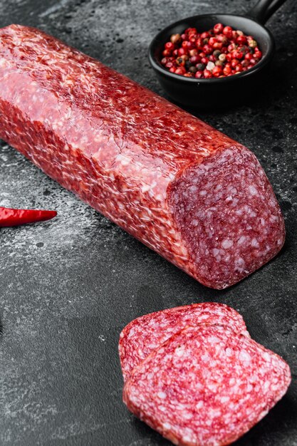 Dry salami sausage with fresh rosemary and spices set, on black dark stone table