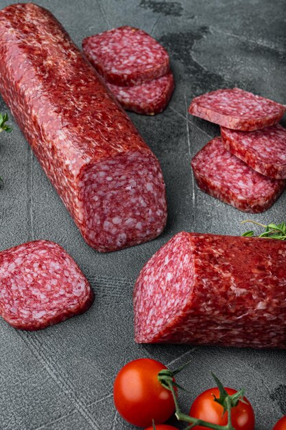 Salame secco con rosmarino fresco e set di spezie, su sfondo grigio tavolo in pietra