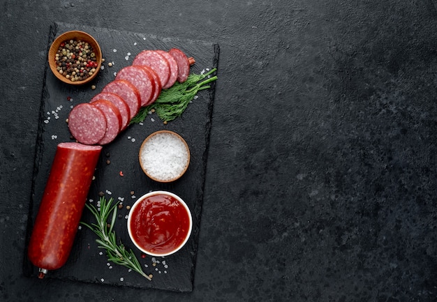 Dry salami sausage with fresh rosemary and spices on a stone