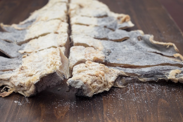 Dry salted cod fish on brown wooden surface