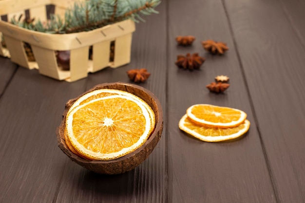 Dry slices of orange in coconut shell Fir branch in a basket