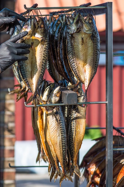 Foto pesce fresco di sgombro affumicato a secco in un mercato del pesce con il venditore che indossa guanti protettivi