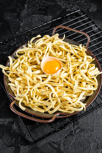 Dry spaetzle egg noodle in a steel tray Black background Top view