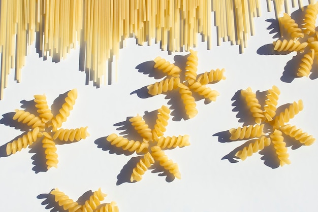 Dry spaghetti pasta and spiral pasta are laid out on a white table The concept of cooking catering